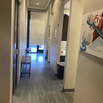 Modern dental office hallway with clean floors, white walls, and contemporary lighting fixtures.